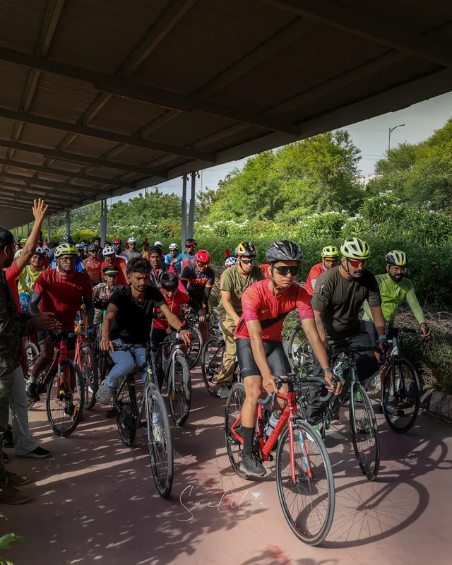 A large group of riders setting off together on a shaded city cycling track